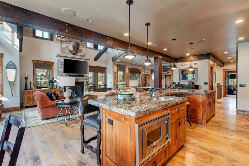 The open-concept kitchen connects seamlessly to the living area, with granite counters, bar seating, and rich wood finishes.