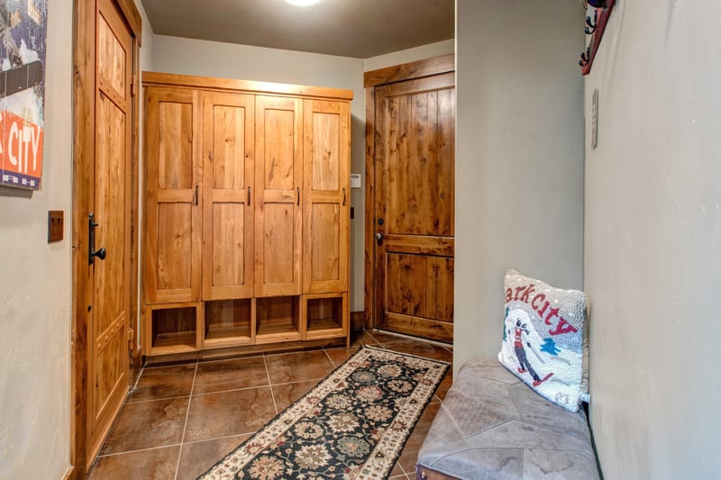 Drop gear with ease in the spacious mudroom, featuring built-in wood lockers, a bench, and tile flooring for easy cleanup.