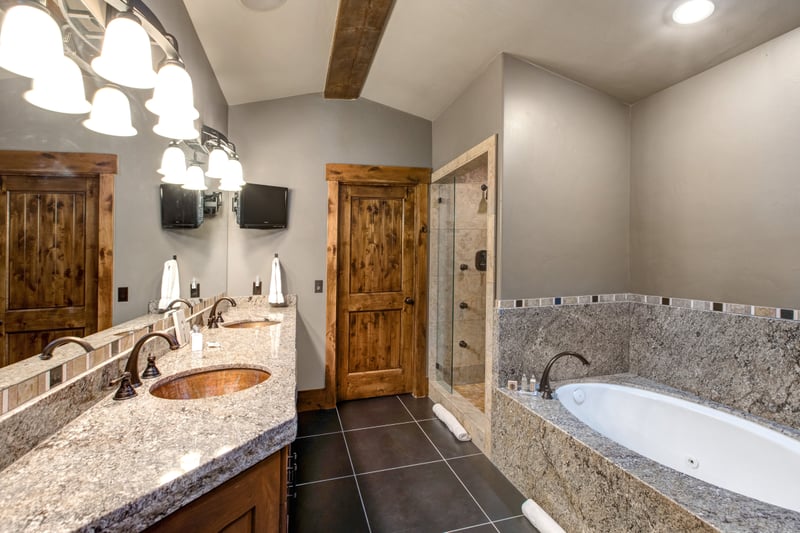 Your ensuite bath features a granite double vanity, soaking tub, and walk-in shower with glass door and wood accents.