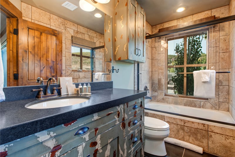 A playful ensuite features a distressed wood vanity, granite counter, and a full-size tub with shower combo.