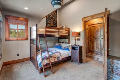 The bunk room includes a Twin-over-Full setup, vibrant bedding, wood furniture, and soft lighting. Perfect for kids or teens.