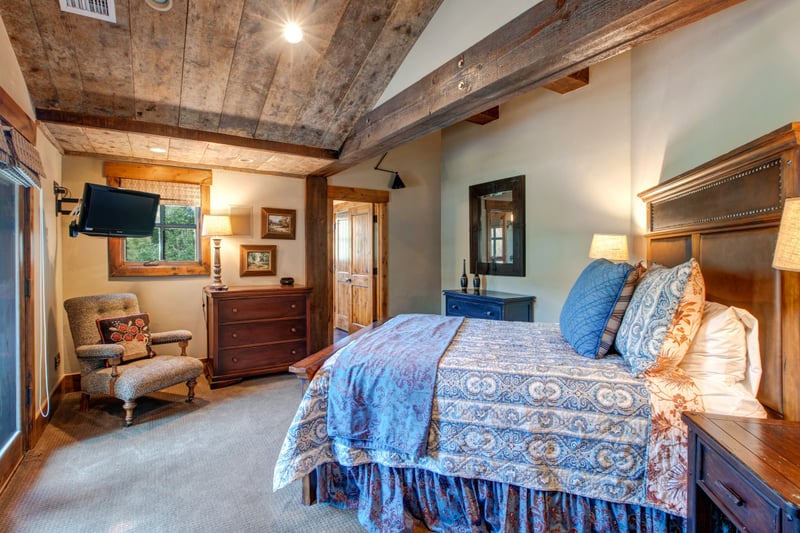 This warm upstairs guest room features a King bed, vaulted ceilings with wood beams, and a cozy reading nook by the window.