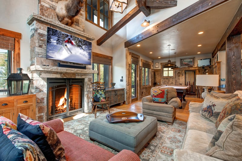 Settle in by the stone fireplace in this inviting great room with soaring ceilings, plush seating, and a large Smart TV.