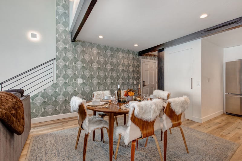 The dining nook features faux fur chairs and a patterned wall, blending comfort and style.