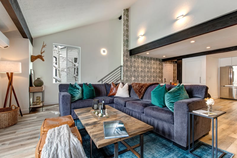 The living view shows plush seating, green feature wall, and mountain-inspired decor.