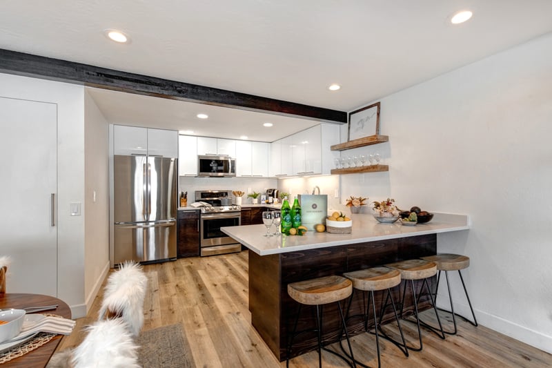 Alternate view of the kitchen with sleek surfaces, gas range, and rustic flooring.