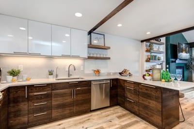 Fully equipped kitchen with stainless appliances, open shelving, and bar seating for three.