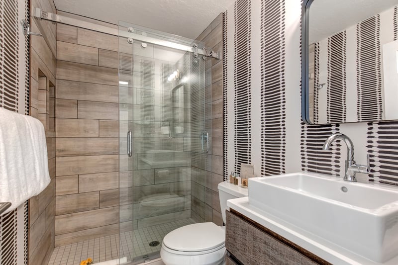The shared bath features a walk-in shower with sleek tile and glass enclosure.