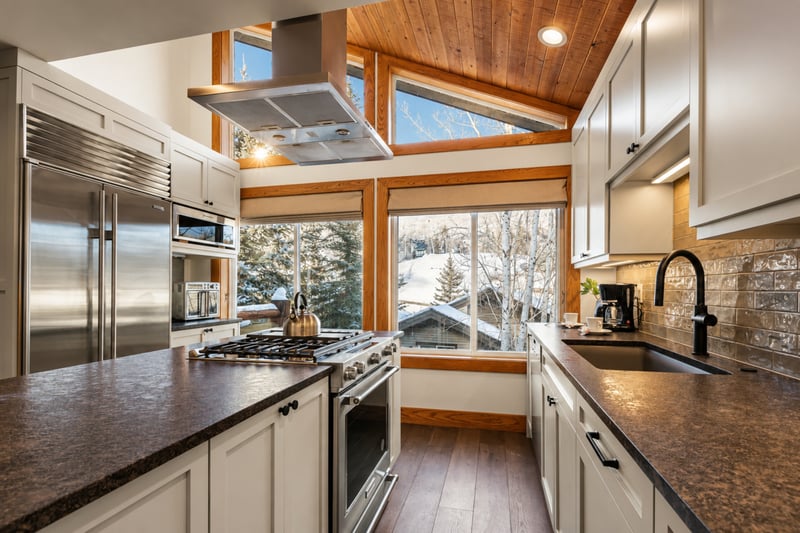 Modern alpine kitchen with scenic windows, vaulted ceiling, and premium appliances.