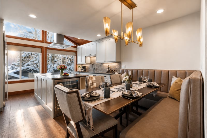 Bright open-concept dining area with elegant lighting and natural flow from kitchen to living room.