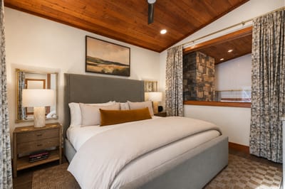 Inviting primary suite with rustic wood ceiling, stone accents, and modern comfort.