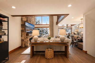 Spacious lodge-inspired interior featuring stone fireplace, mountain views, and stylish dining area.