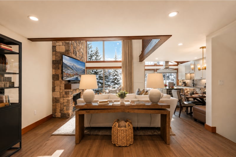 Spacious lodge-inspired interior featuring stone fireplace, mountain views, and stylish dining area.