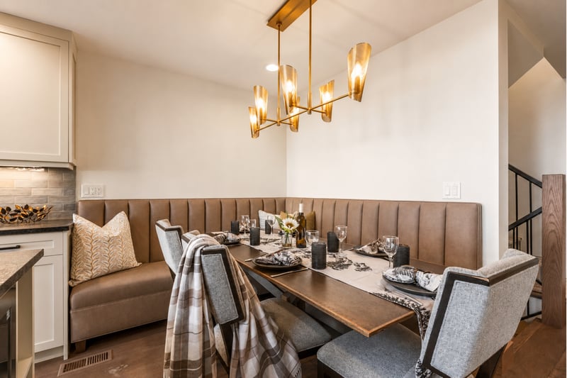 Chic corner dining nook with plush seating, golden lighting, and elegant mountain décor.