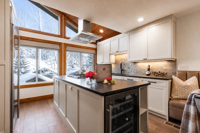 Airy kitchen with vaulted ceiling, scenic windows, and cozy breakfast bench.