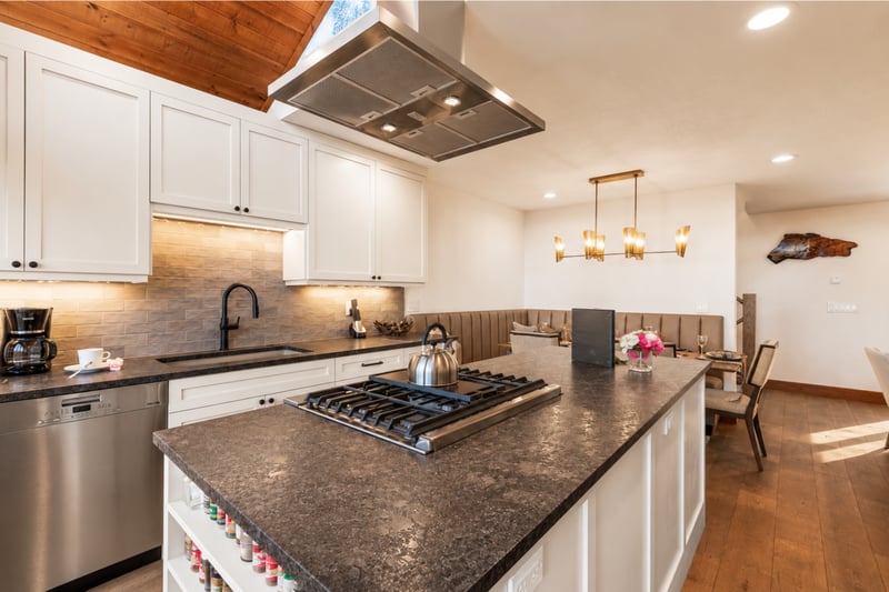 Sleek modern kitchen with island cooktop, minimalist cabinetry, and integrated dining area.