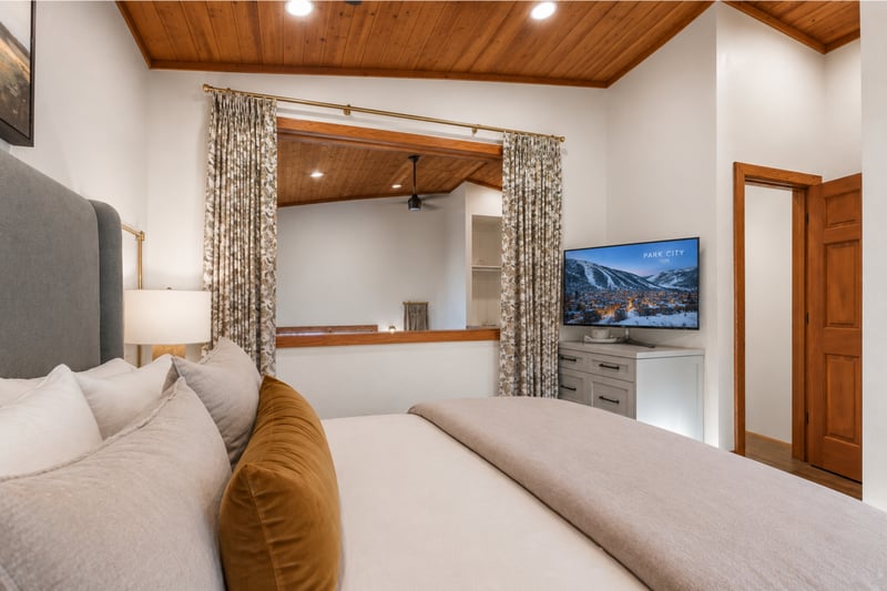 Elegant bedroom with king bed, warm wood details, and TV.