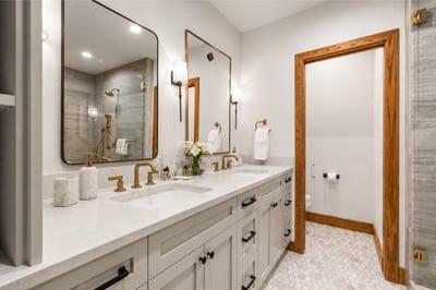 Elegant ensuite bath with dual vanity, gold fixtures, and spa-style finishes.