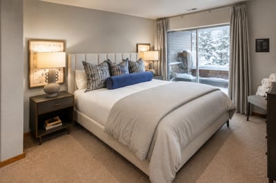 Relaxing guest bedroom with plush bedding, sliding glass door, and serene natural views.