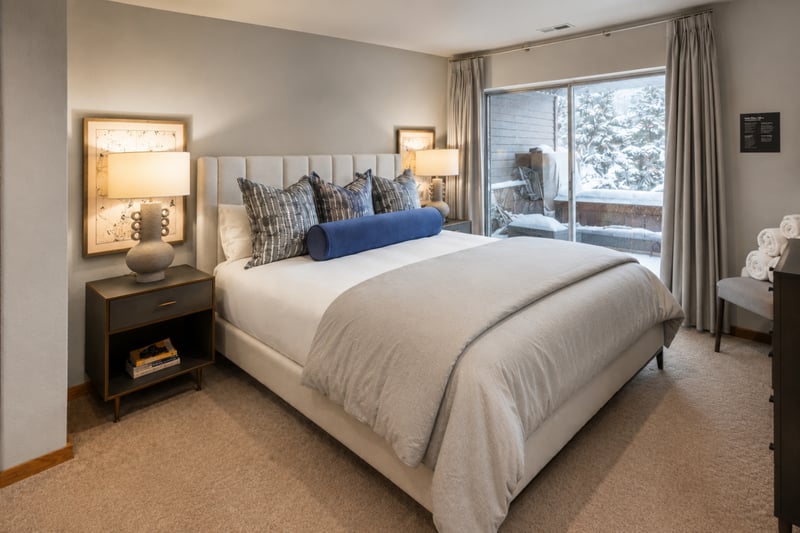 Relaxing guest bedroom with plush bedding, sliding glass door, and serene natural views.