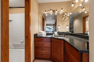 Contemporary guest bathroom with rich wood cabinetry, granite counters, and crisp lighting.
