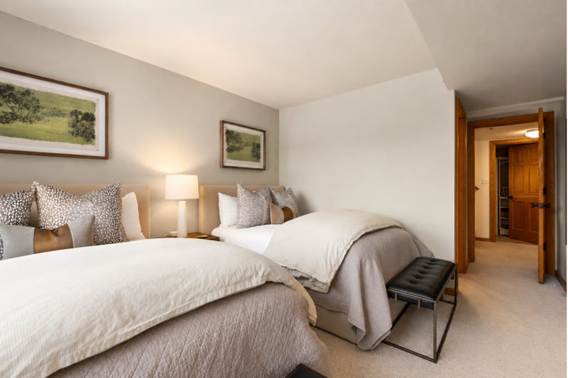 Elegant guest room with two double beds, soft lighting, and peaceful neutral tones.