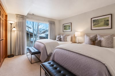 Twin guest room featuring forest views, natural light, and stylish cozy linens.
