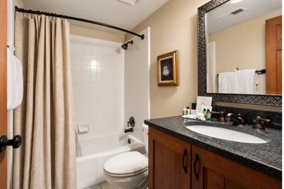 Traditional full bathroom with granite countertop, framed mirror, and tub/shower combo.
