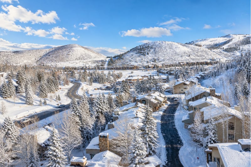 Scenic view of Deer Valley nestled in snowy mountains under a crystal-clear winter sky.