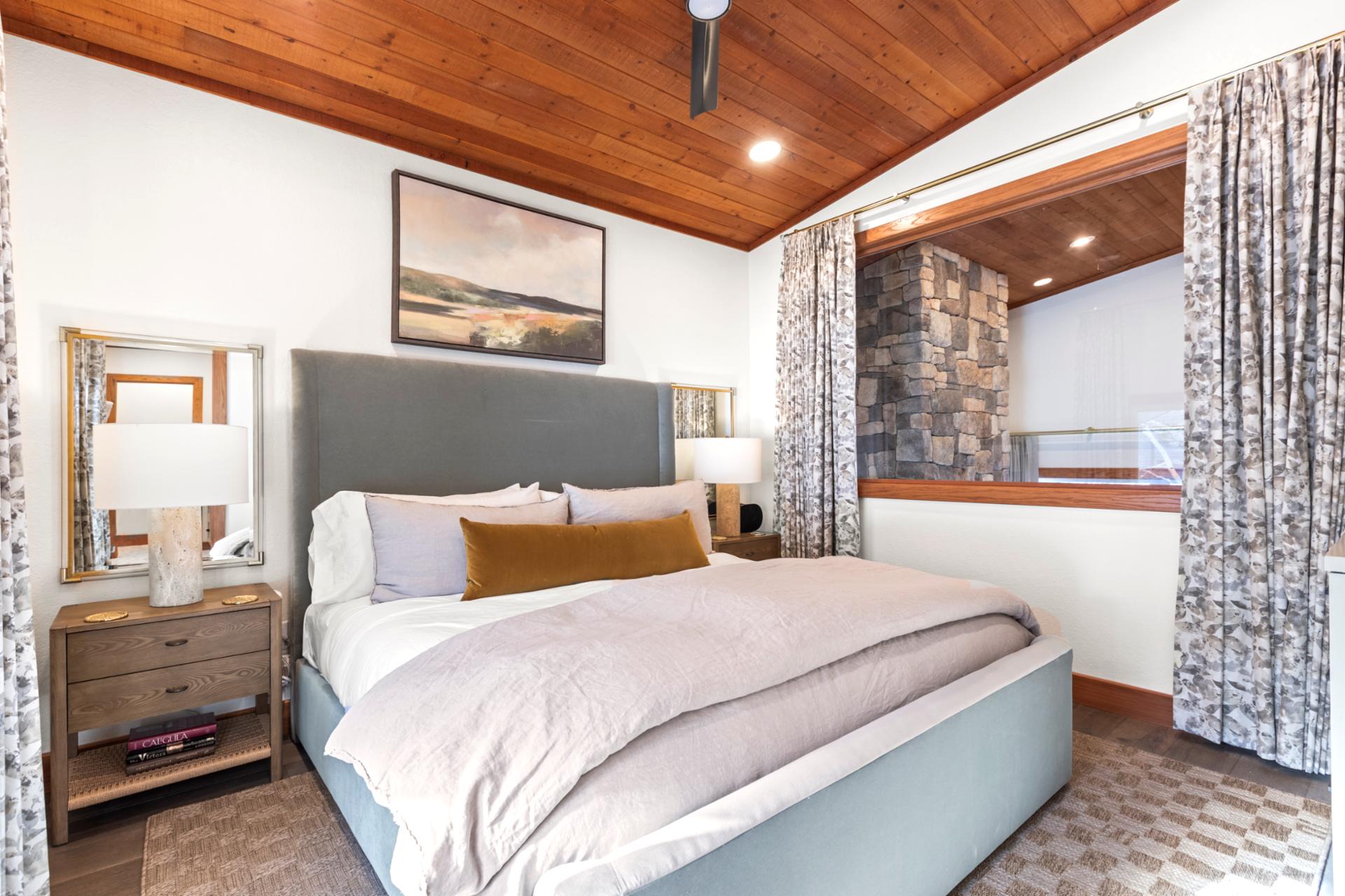 Inviting primary suite with rustic wood ceiling, stone accents, and modern comfort.