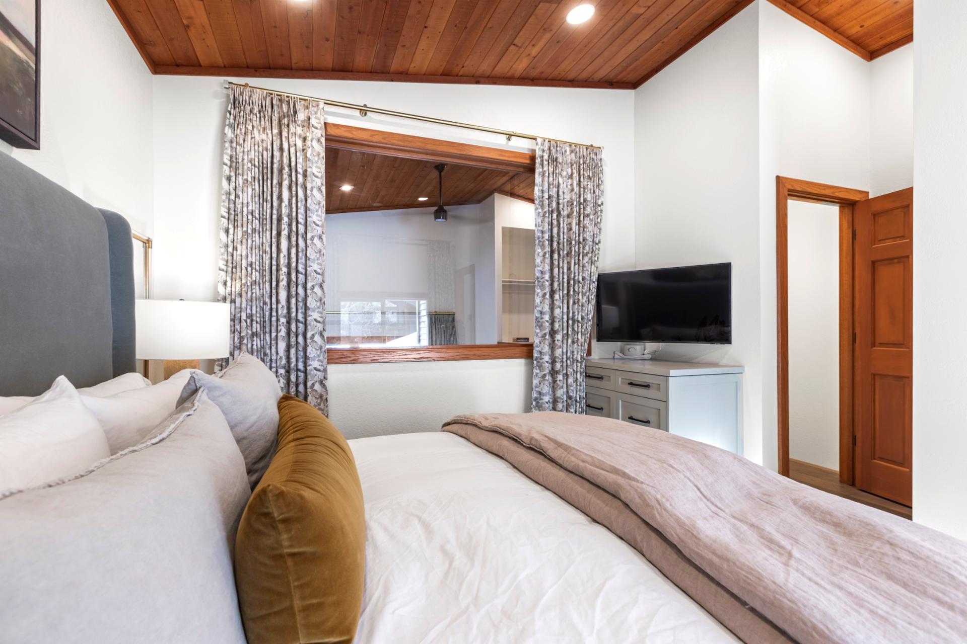 Charming lofted bedroom with king bed, warm wood details, and built-in TV nook.