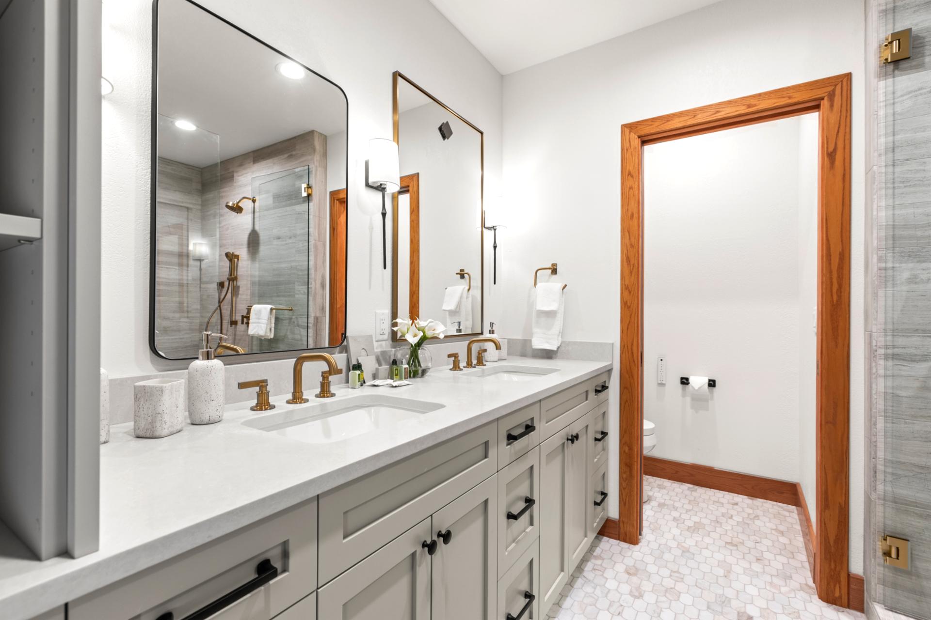 Elegant ensuite bath with dual vanity, gold fixtures, and spa-style finishes.