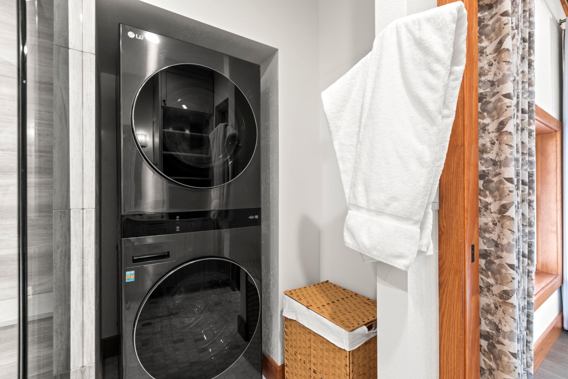 Sleek laundry space with stacked LG washer-dryer, wicker basket, and robe storage.