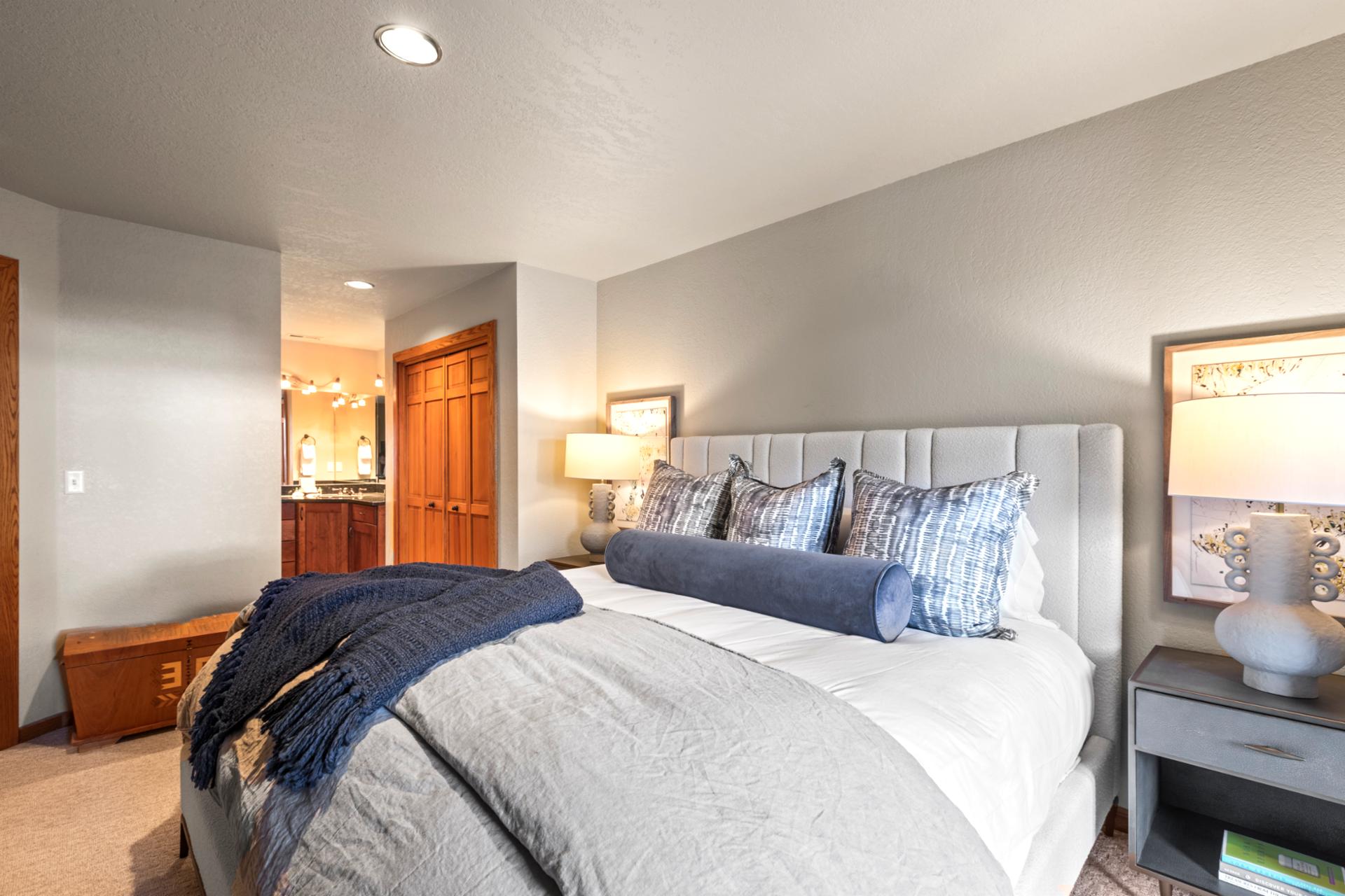 Peaceful guest room with king bed, ensuite access, and warm, ambient lighting.