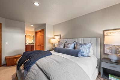 Peaceful guest room with king bed, ensuite access, and warm, ambient lighting.