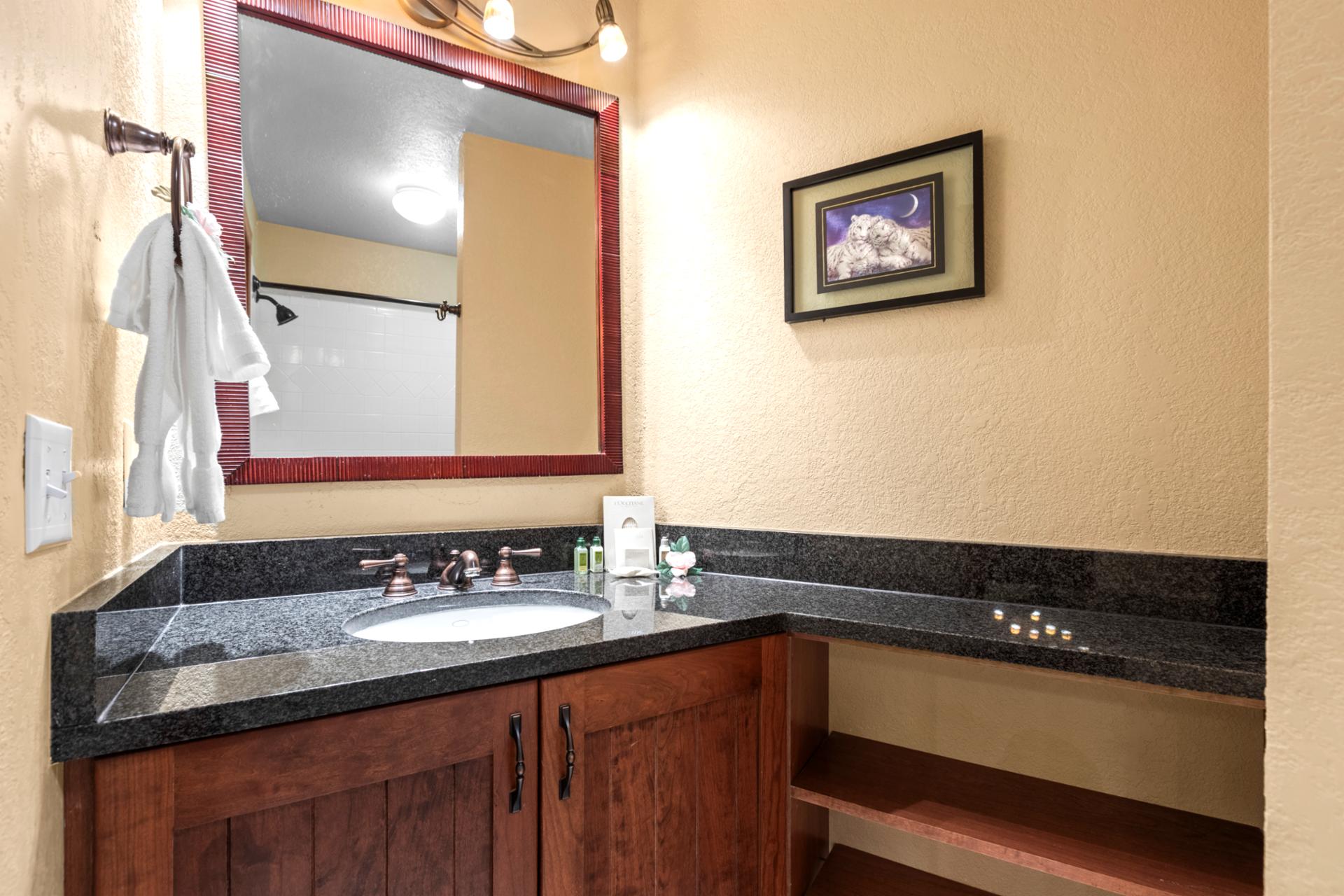 Cozy bathroom with granite vanity, bronze fixtures, and warm ambient lighting.