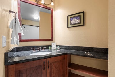 Cozy bathroom with granite vanity, bronze fixtures, and warm ambient lighting.