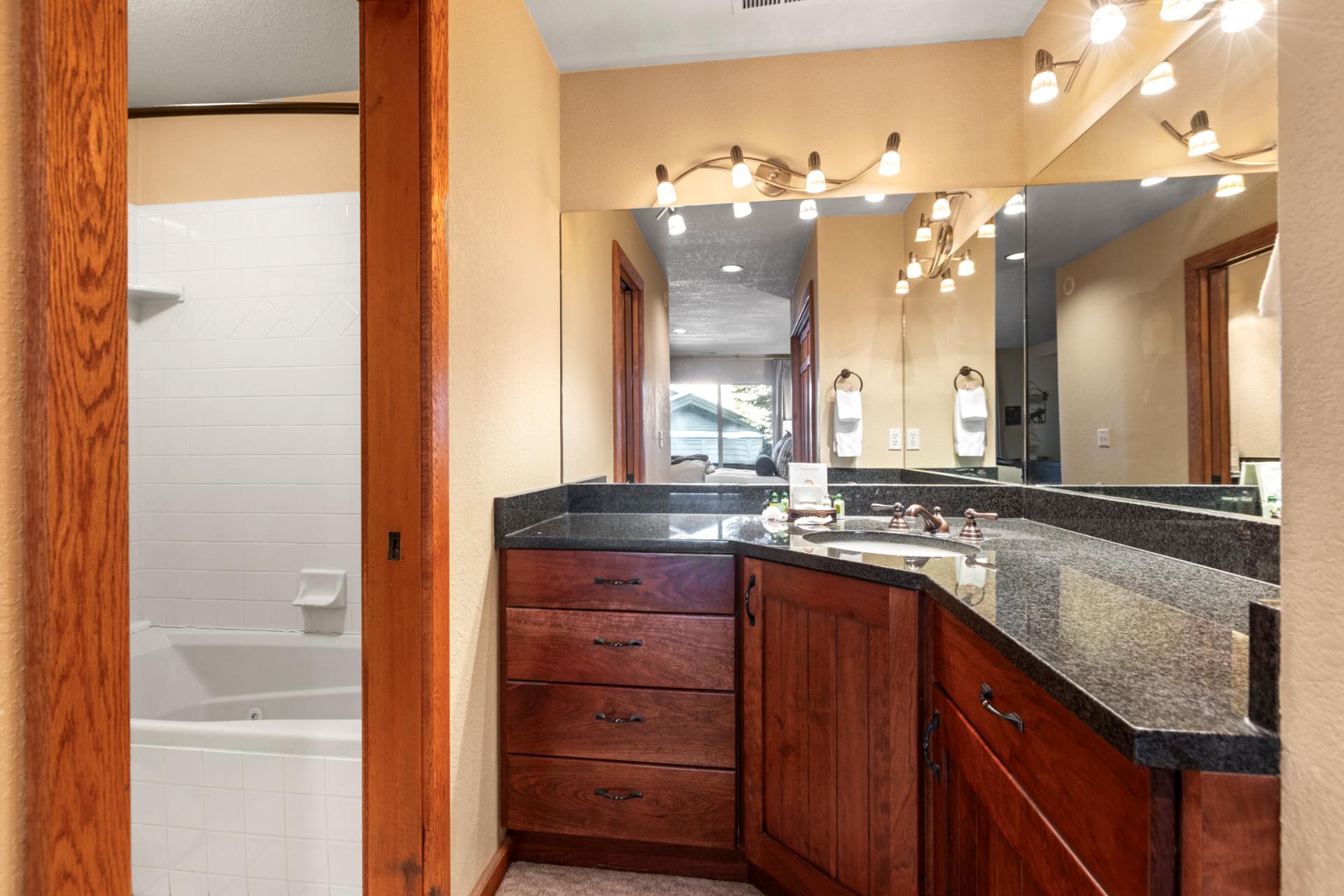 Contemporary guest bathroom with rich wood cabinetry, granite counters, and crisp lighting.