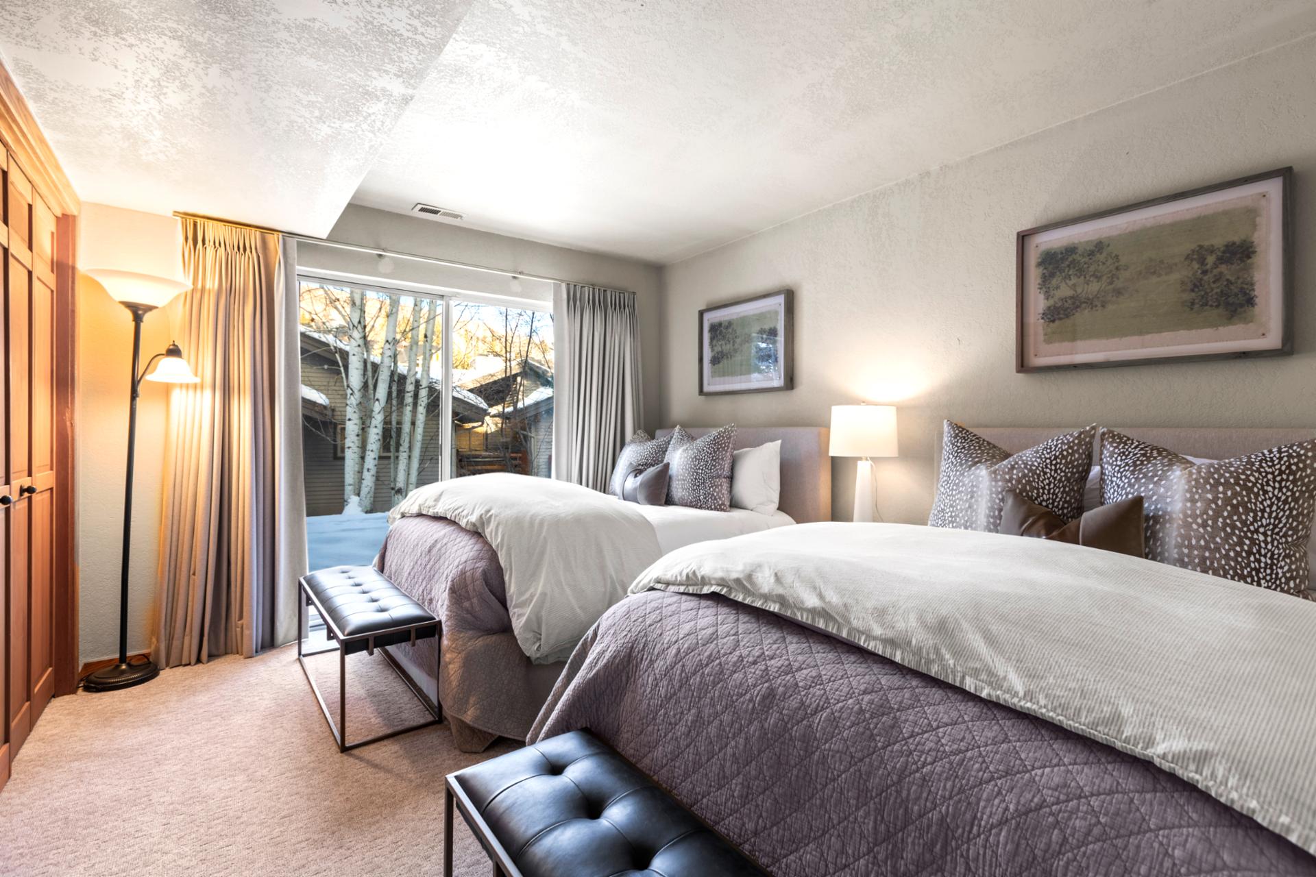 Twin guest room featuring forest views, natural light, and stylish cozy linens.