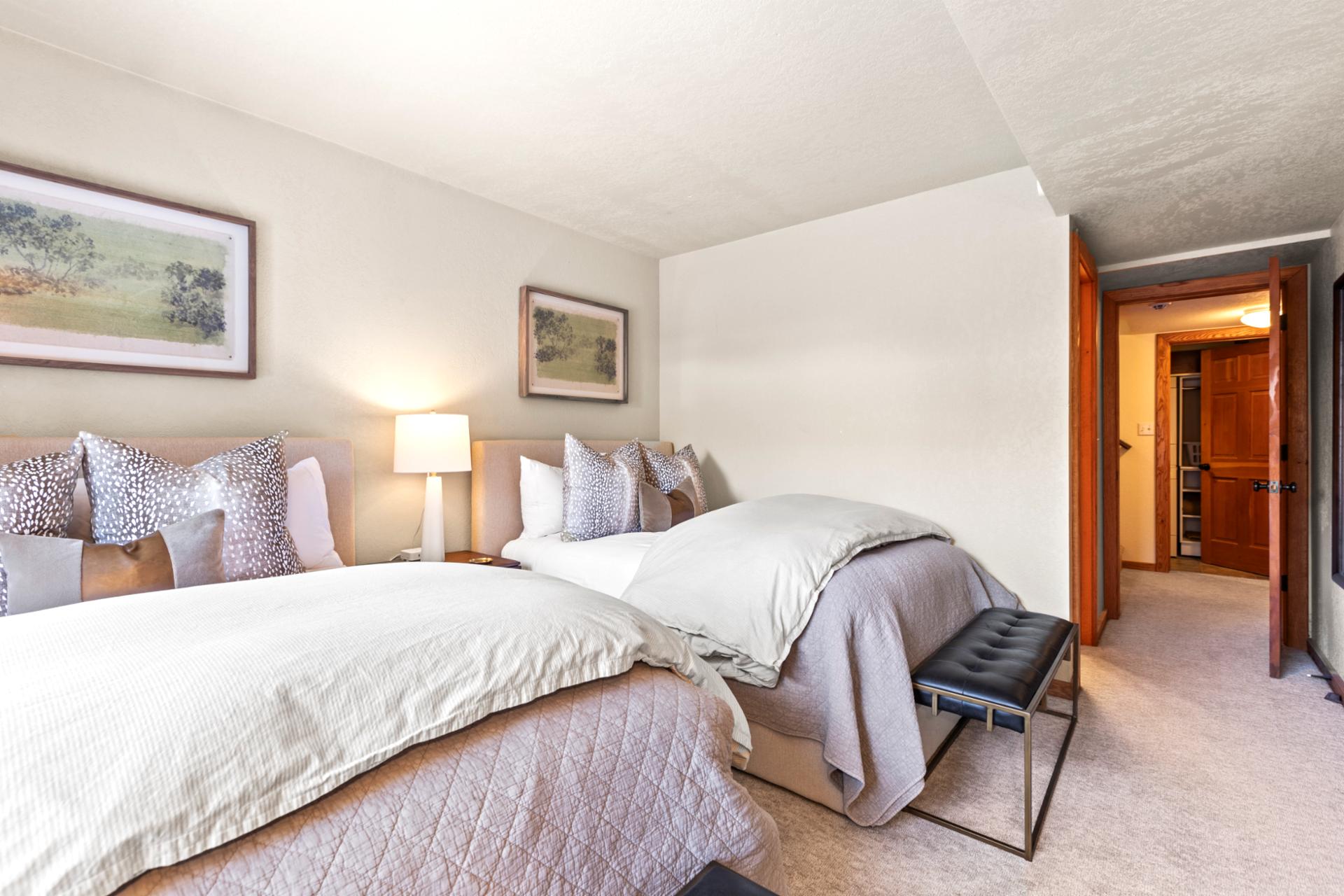 Elegant guest room with twin beds, soft lighting, and peaceful neutral tones.