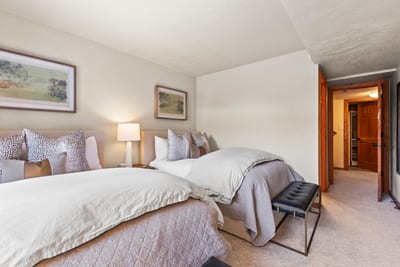 Elegant guest room with twin beds, soft lighting, and peaceful neutral tones.