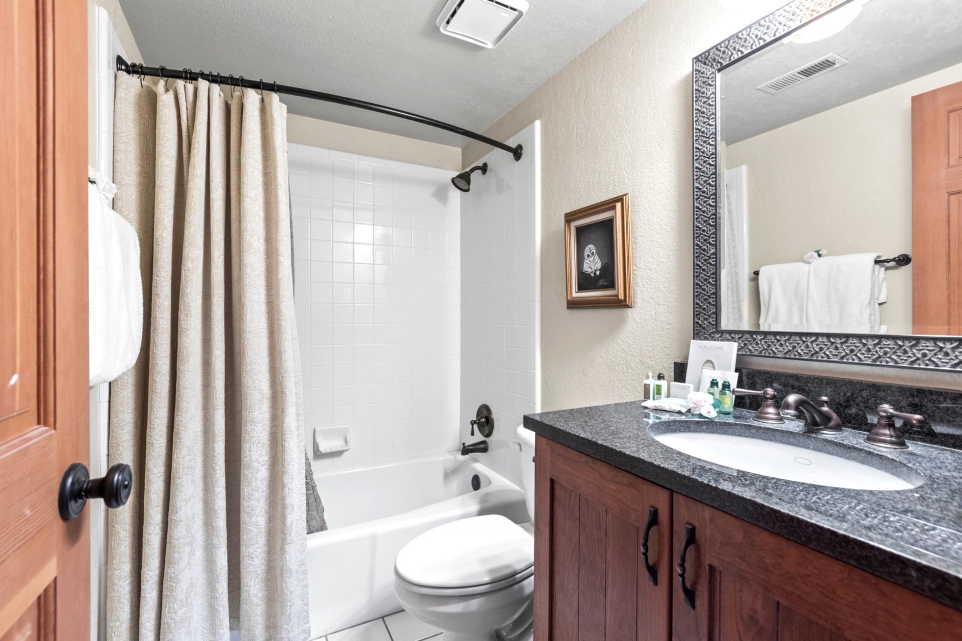 Traditional full bathroom with granite countertop, framed mirror, and tub/shower combo.