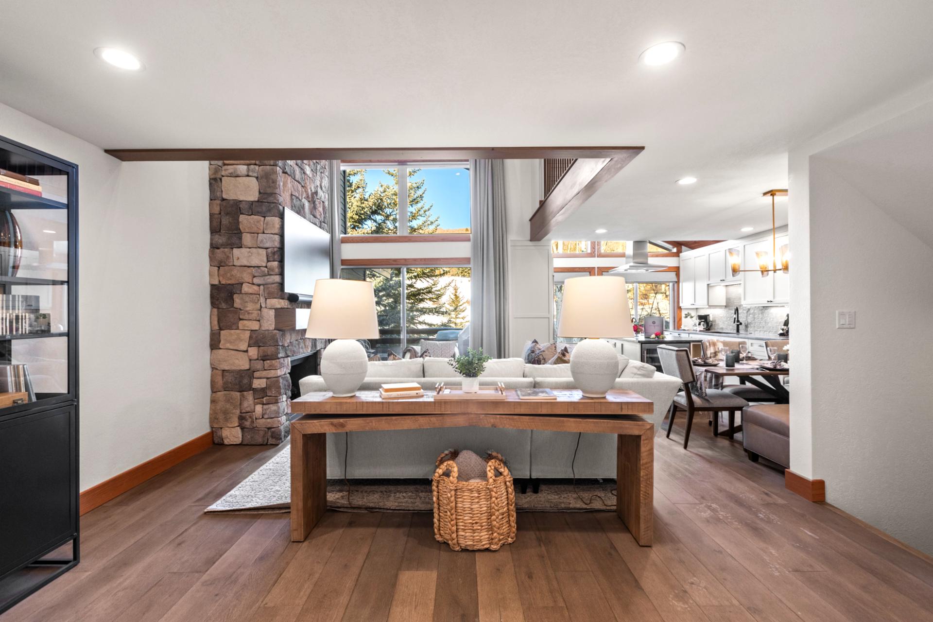 Spacious lodge-inspired interior featuring stone fireplace, mountain views, and stylish dining area.