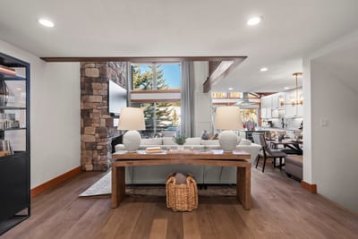 Spacious lodge-inspired interior featuring stone fireplace, mountain views, and stylish dining area.