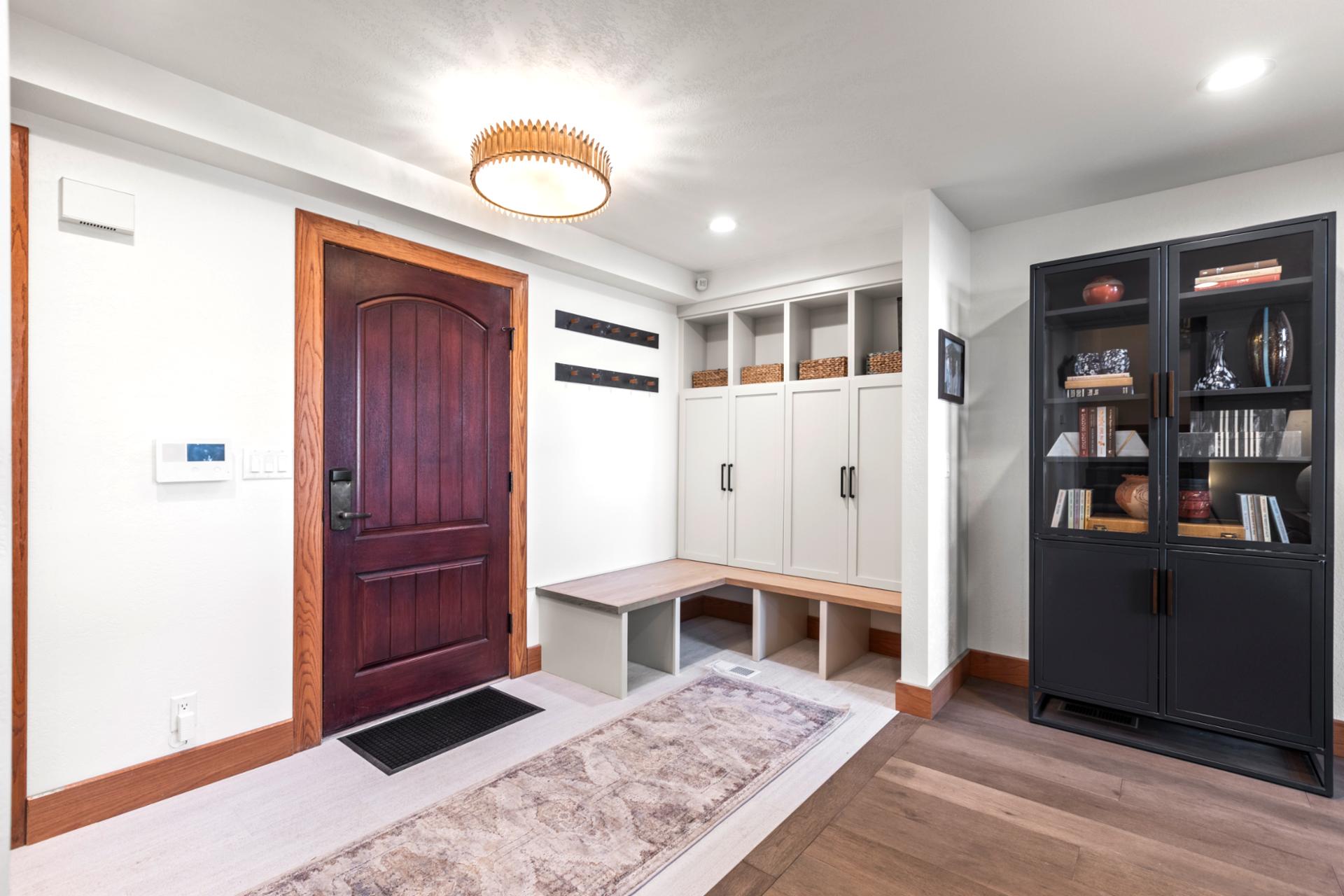 Functional and bright entryway featuring built-in storage, coat hooks, and contemporary bookshelf.