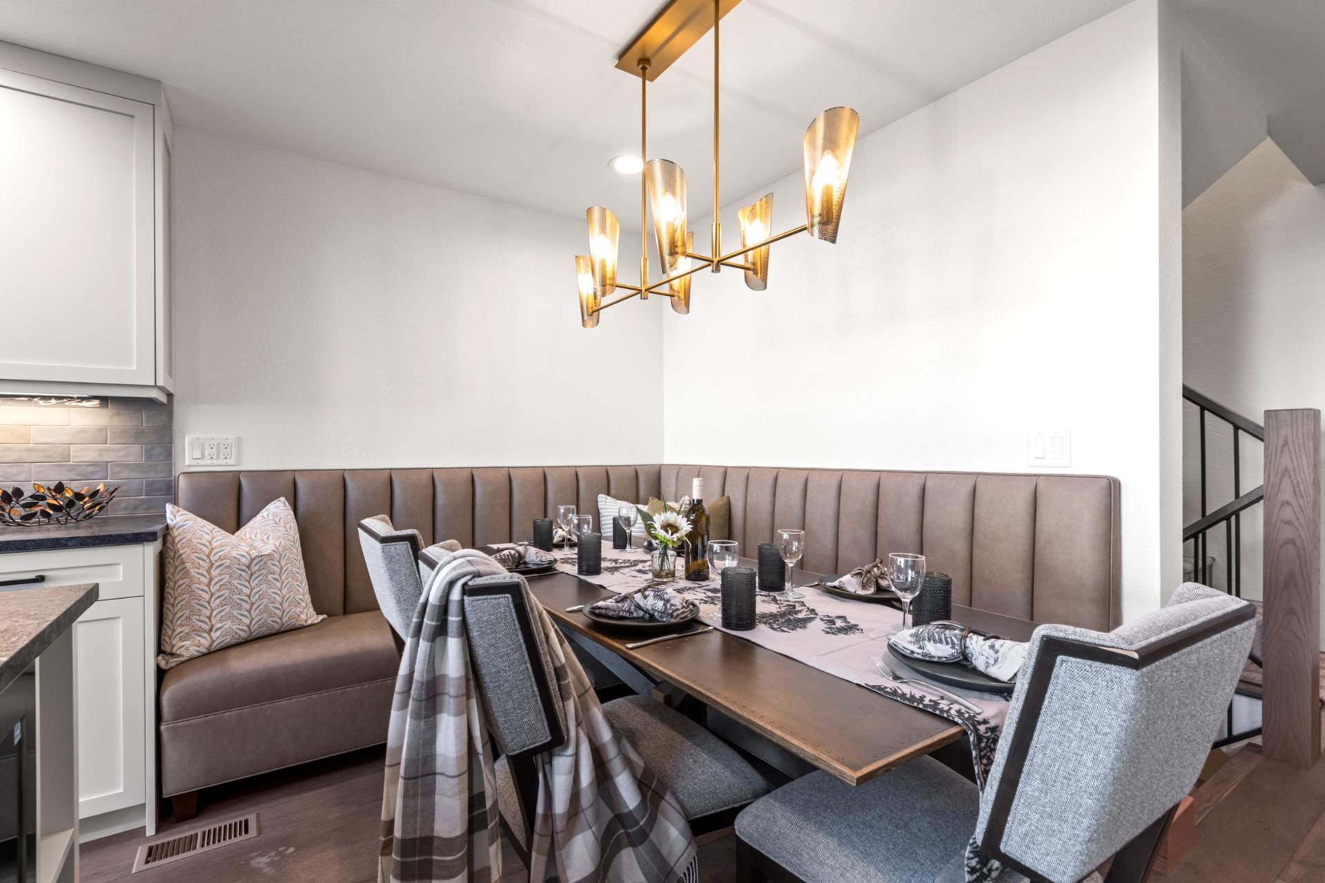 Chic corner dining nook with plush seating, golden lighting, and elegant mountain décor.