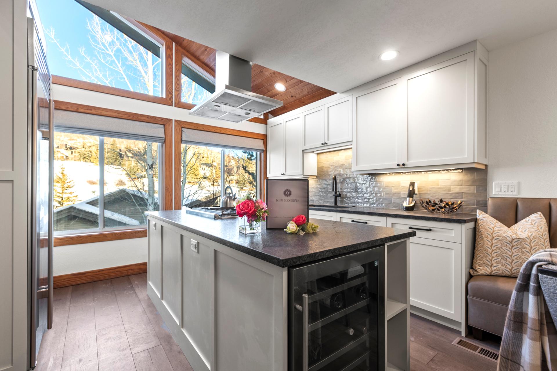 Airy kitchen with vaulted ceiling, scenic windows, and cozy breakfast bench.