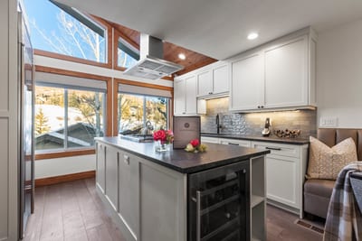 Airy kitchen with vaulted ceiling, scenic windows, and cozy breakfast bench.