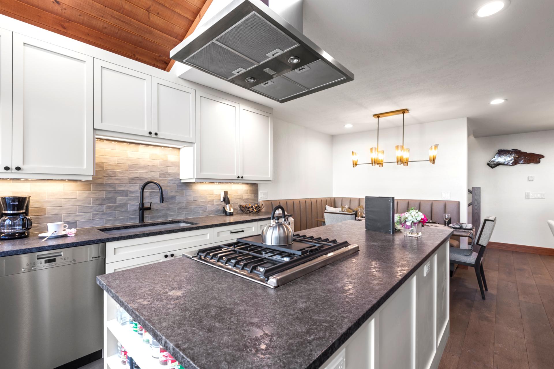 Sleek modern kitchen with island cooktop, minimalist cabinetry, and integrated dining area.