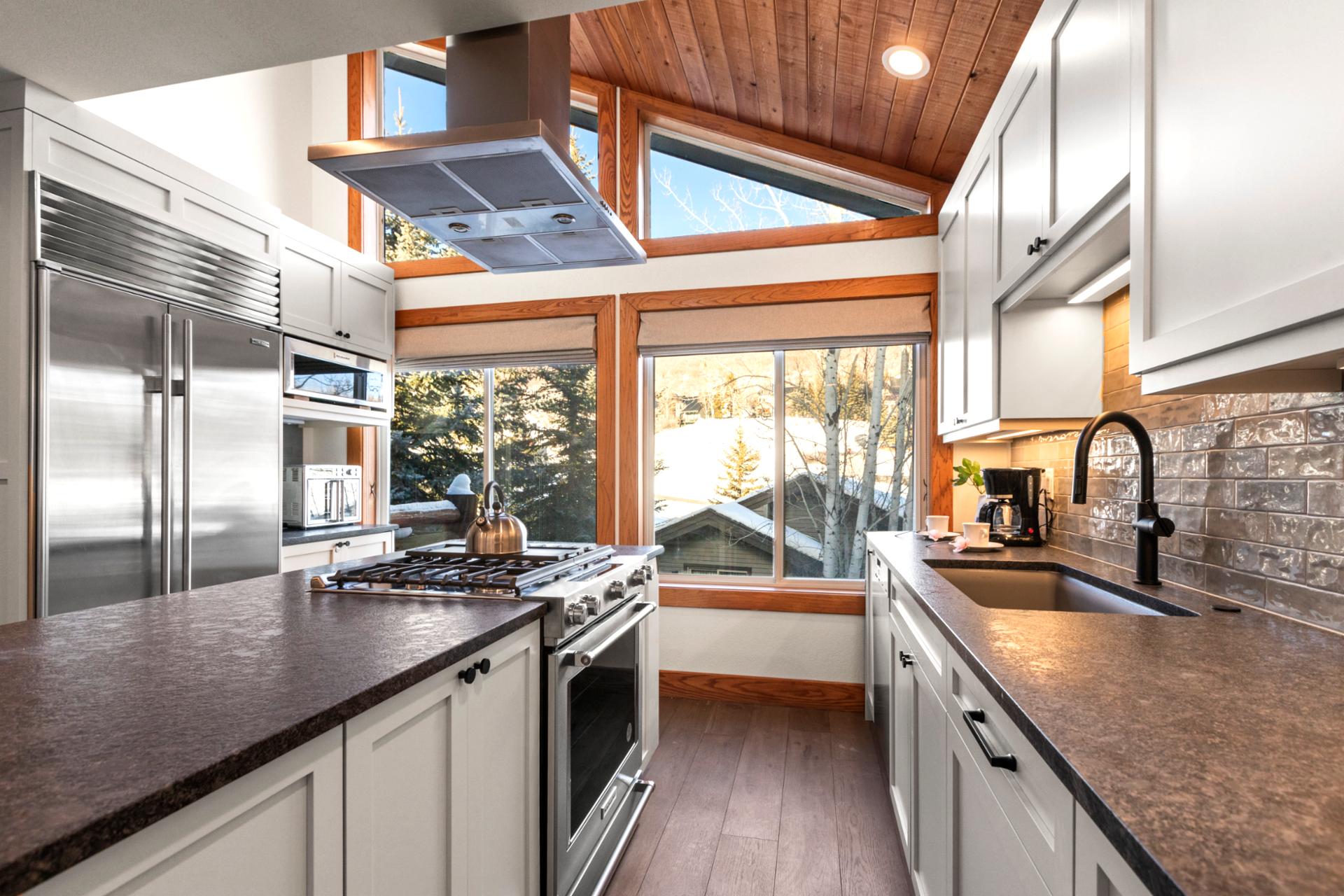 Modern alpine kitchen with scenic windows, vaulted ceiling, and premium appliances.